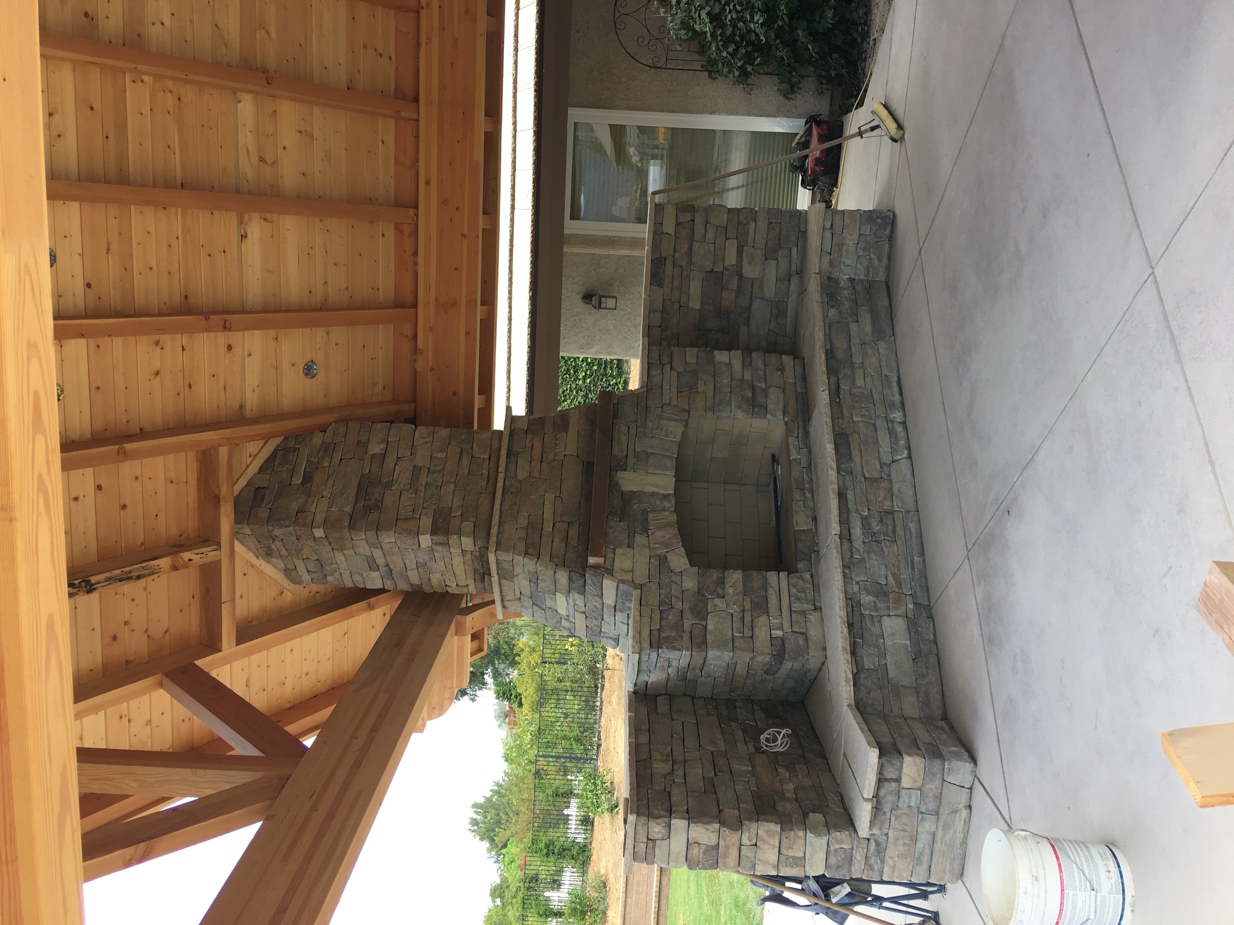 Large stone fireplace under timber pergola